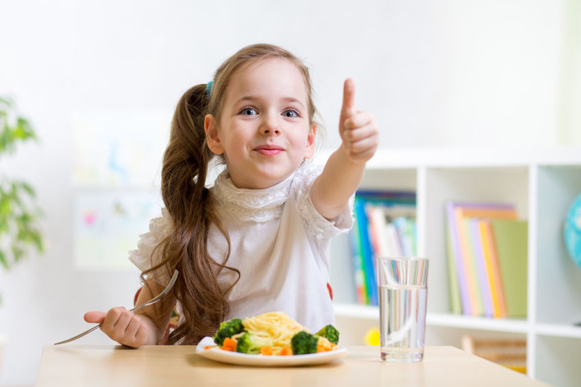 child girl eats healthy food showing thumb up