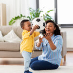 mother and baby playing with soccer ball at home
