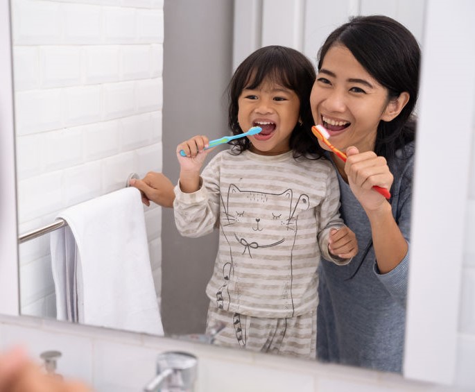 Routines-happy attractive mom and kid brushing their teeth