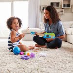 Young black mum plays ukulele with toddler daughter