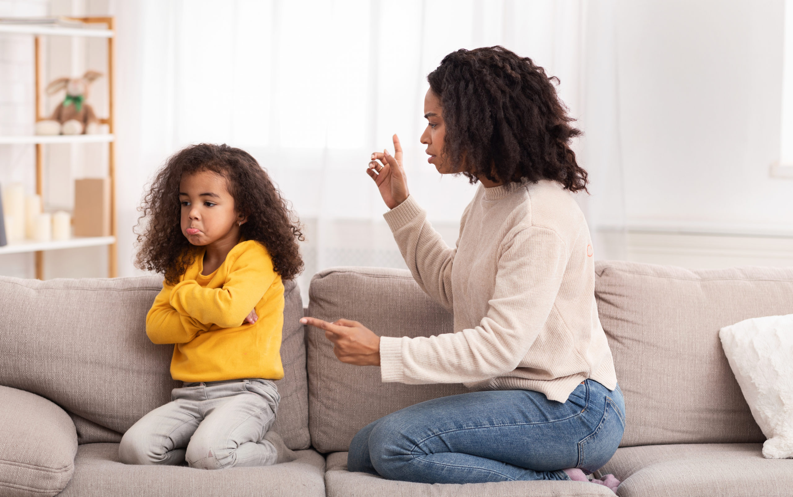 Angry Black Mother Scolding Kid Shouting At Sad Daughter Sitting On Sofa At Home. Family Quarrels And Problems