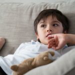 Child putting finger in his mouth. Schoolboy biting his finger n