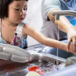Girl and mom washing dishes