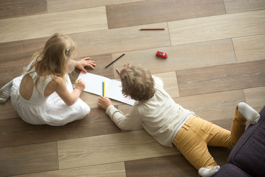 Kids sister and brother playing drawing together on wooden warm floor in living room, creative children boy and girl having fun at home, siblings friendship, underfloor heating concept, top view