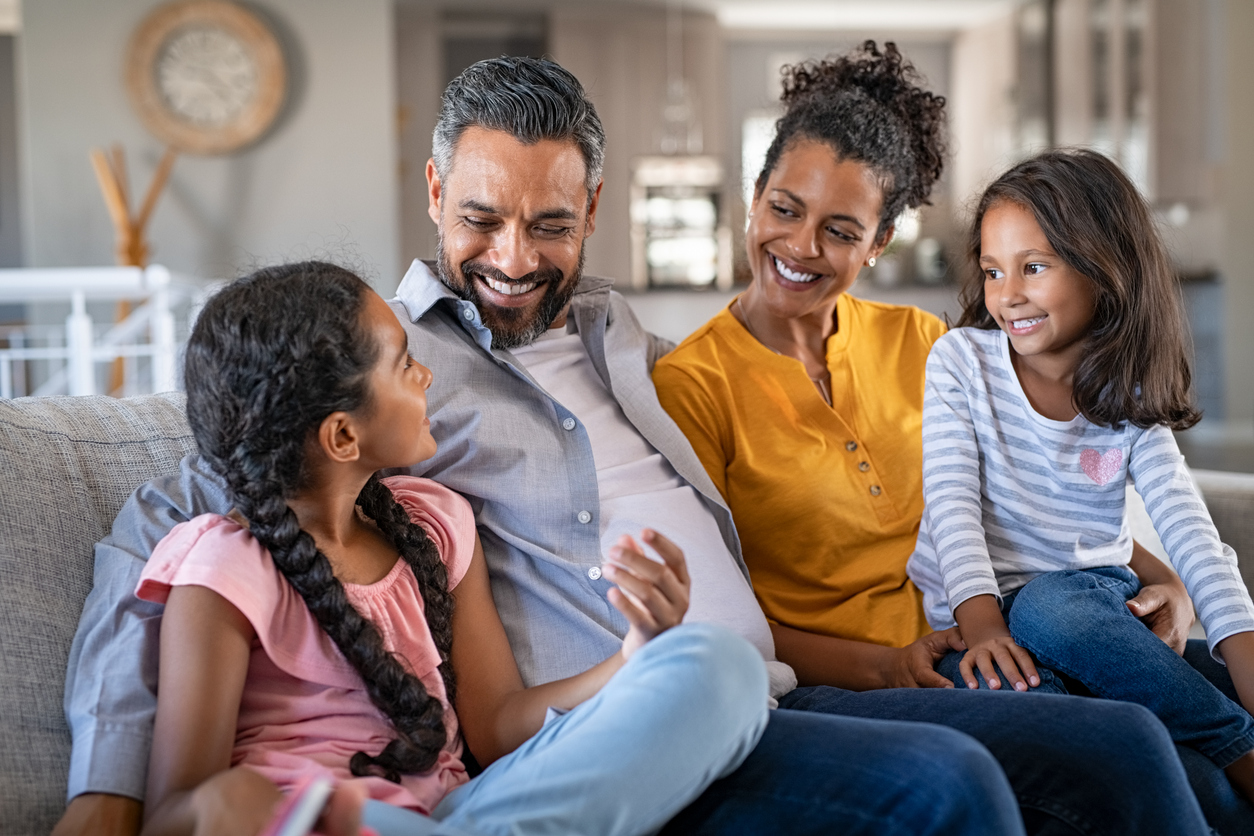 happy parents on couch with daughters, Get on the Same Page: Practical Steps to Resolve Parenting Style Conflicts