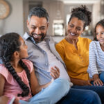 happy parents on couch with daughters